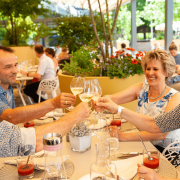 Gäste sitzen an einem Tisch auf einer überdachten Restaurant Terrasse, gute Stimmung, die Gäste stoßen an